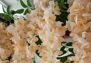 Close-up detail of artificial wisteria hanging flower vine, champagne pink silk floral decor.