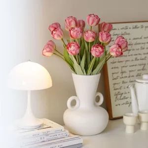 Detailed view of elegant artificial tulips in a white ceramic vase for home decor.