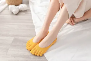 Detailed close-up of yellow five-toe socks worn by model, soft breathable cotton.