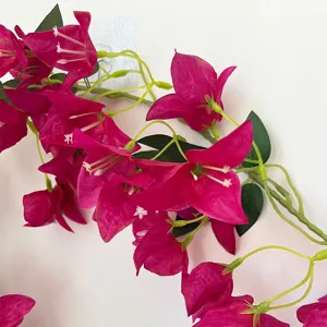 Primer plano de vid de buganvilla artificial, pétalos de flores rosas vibrantes y hojas verdes.