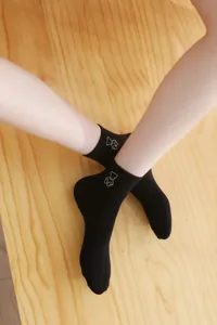 Detailed shot of cute black short socks with adorable bear embroidery worn on legs.