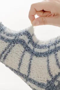 Close-up of soft fluffy fleece socks fabric texture, thick checkered winter comfort detail.