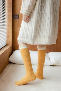 Nahaufnahme kuscheliger gelber Korallenfleece Kniestrümpfe mit weißen gestreiften Bündchen.