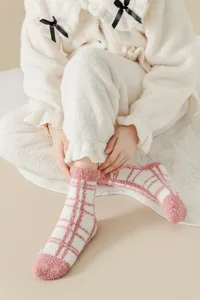 Detail shot of fluffy coral fleece winter socks showcasing the soft pink and white plaid texture.