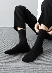 Close-up detail of men's black ribbed mid-calf socks, showing stretchy knit texture.