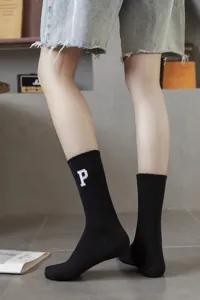 Detailed close-up shot of black ribbed crew socks featuring white embroidered letter P design.