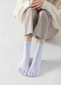 Close-up detail view of white five-toe yoga socks, comfortable cotton knit for fitness wear.