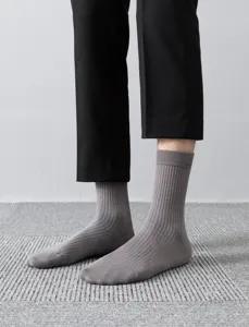 Detailed close-up shot of men's gray ribbed mid-calf socks worn by a model, showing fine texture.