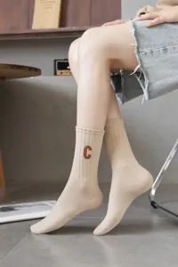 Detail view of women solid color ribbed mid tube socks featuring brown letter embroidery.