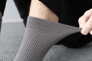 Close-up detail of grey men's ribbed mid-calf socks showing high elasticity and soft knit texture.