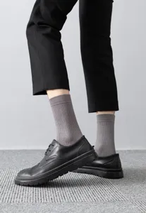 Close-up detail shot of men's grey ribbed mid-calf socks paired with stylish black shoes.