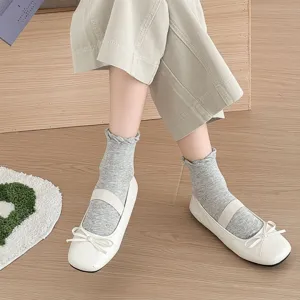 Close-up view of grey hollow ruffled mid-tube socks paired with elegant white ballet flat shoes.