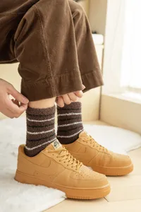 Detailed close-up of brown striped thick coral fleece men's sleep socks worn indoors.