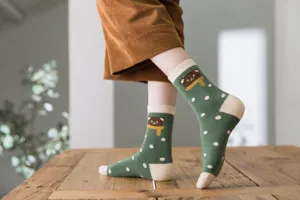 Close-up detail of green winter cotton socks featuring cute bear and polka dot patterns.