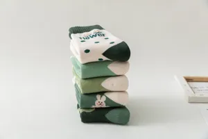 Detailed view of stacked green and white thermal loop socks with cute patterns, soft and cozy.