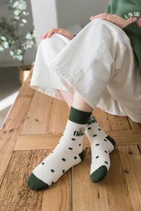 Detailed shot of women's white terry socks featuring green polka dots and cute flower print.
