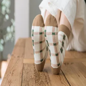 Close-up detail shot of women's autumn winter cozy plaid looped socks on wooden floor background.