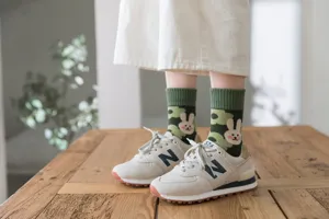 Detail view of women green terry socks featuring cute rabbit and flower pattern, warm fabric.