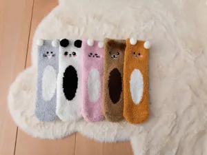 Close-up detail of cozy cartoon coral fleece socks with cute animal ears for warm indoor wear.