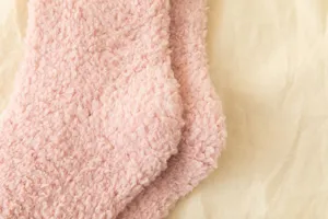 Close-up view of soft pink coral fleece fuzzy warm winter socks fabric texture detail.