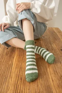 Close-up of cozy green and white striped fuzzy coral fleece socks, warm and soft texture.