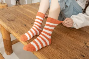 Detailed shot of cozy coral fleece fuzzy socks with orange and white stripes for warmth.