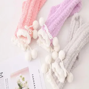 Detailed view of fluffy coral fleece socks with pom-poms in pink, purple, and grey cozy winter.