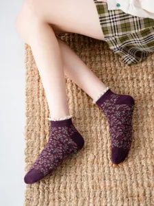 Close-up detail shot of retro floral short socks featuring white lace trim on woven mat.