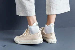 Detailed view of women white boat socks featuring cute avocado embroidery, paired with casual canvas shoes.