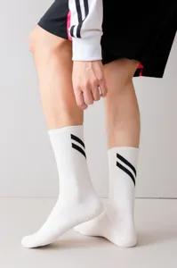 Detalle de calcetines deportivos blancos para hombre con rayas negras y suela de silicona.