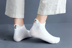 Close-up detail of white women ankle socks featuring a cute 3D peach embroidery design.
