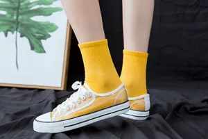 Calzini da donna gialli a coste abbinati a scarpe casual trasparenti alla moda.