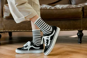 Detailed view of women's black and white striped cotton socks paired with casual sneakers.
