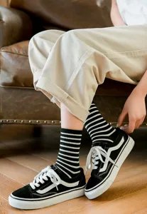 Women's classic black and white striped cotton socks with casual canvas sneakers detail view.