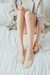 Detail shot of women summer ice silk shallow invisible boat socks worn on white bed.