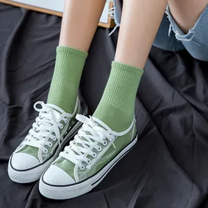 Calze verdi da donna a metà polpaccio abbinate a scarpe di tela trasparenti e casual.