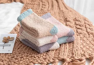 Close up detail shot of fluffy coral fleece socks stacked on cozy knit blanket for winter.