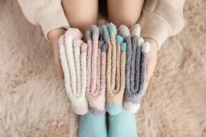 Detailed close-up shot of colorful cozy fleece sleep socks held in hands, soft winter texture.