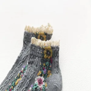 Detail view of women's grey knit short socks featuring vintage floral embroidery and delicate lace trim.