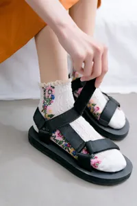 Close-up detail of Japanese floral lace socks paired with casual black velcro strap sandals.