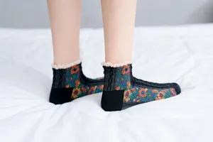 Close-up detail of vintage floral ankle socks with delicate lace trim on clean white bed.