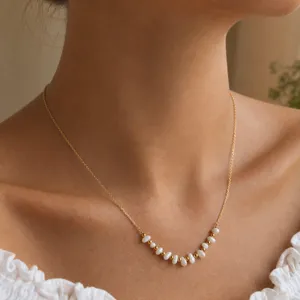 Delicate close-up of shell bead and gold bead U-shaped necklace detail, elegant jewelry design.