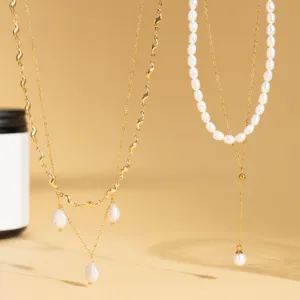 Detail view of layered baroque pearl necklaces with gold chains hanging against a warm backdrop.