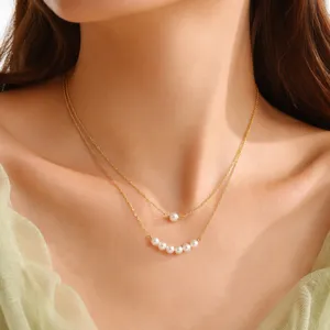 Detail shot of a double layer pearl collarbone necklace featuring dainty gold chains and pearls.