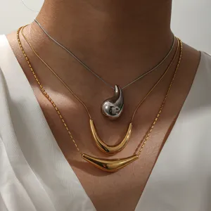 Detailed close-up of layered titanium steel necklaces with a silver drop and gold pendants.