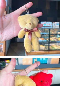 Close-up detail of plush bear keychain with ribbon bow and metal bead chain for cute bag decor.