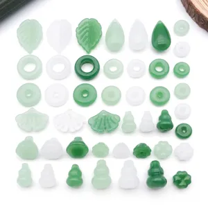 Detailed view of assorted green and white glass DIY jewelry beads, leaf and clover pendants.