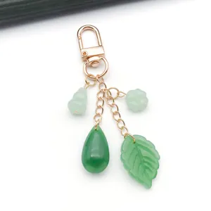 Close-up detail of green glass leaf and gourd charms with rose gold clasp, DIY pendant accessory.
