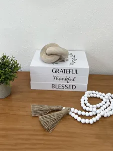 Decorative faux book storage box with wood knot and tassel for rustic home tabletop decor.