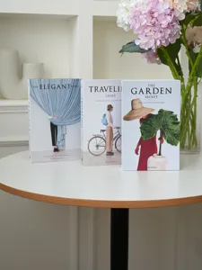 Close-up of decorative simulation books on a white table with floral vase, ins style photo prop.